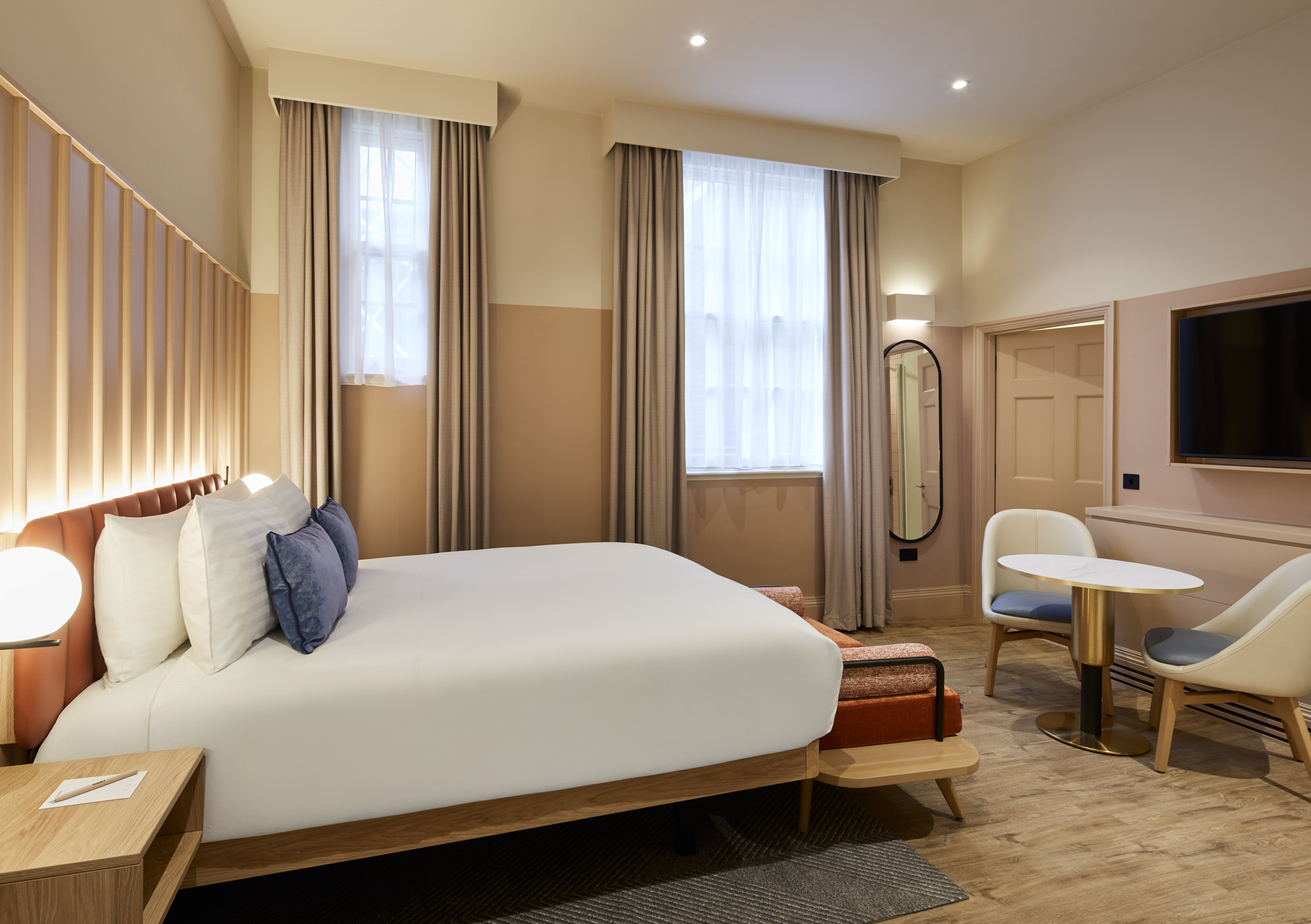 Inviting studio at master Cannon London with a large bed, stylish seating area, soft curtains, and a flat-screen TV for a relaxing stay.