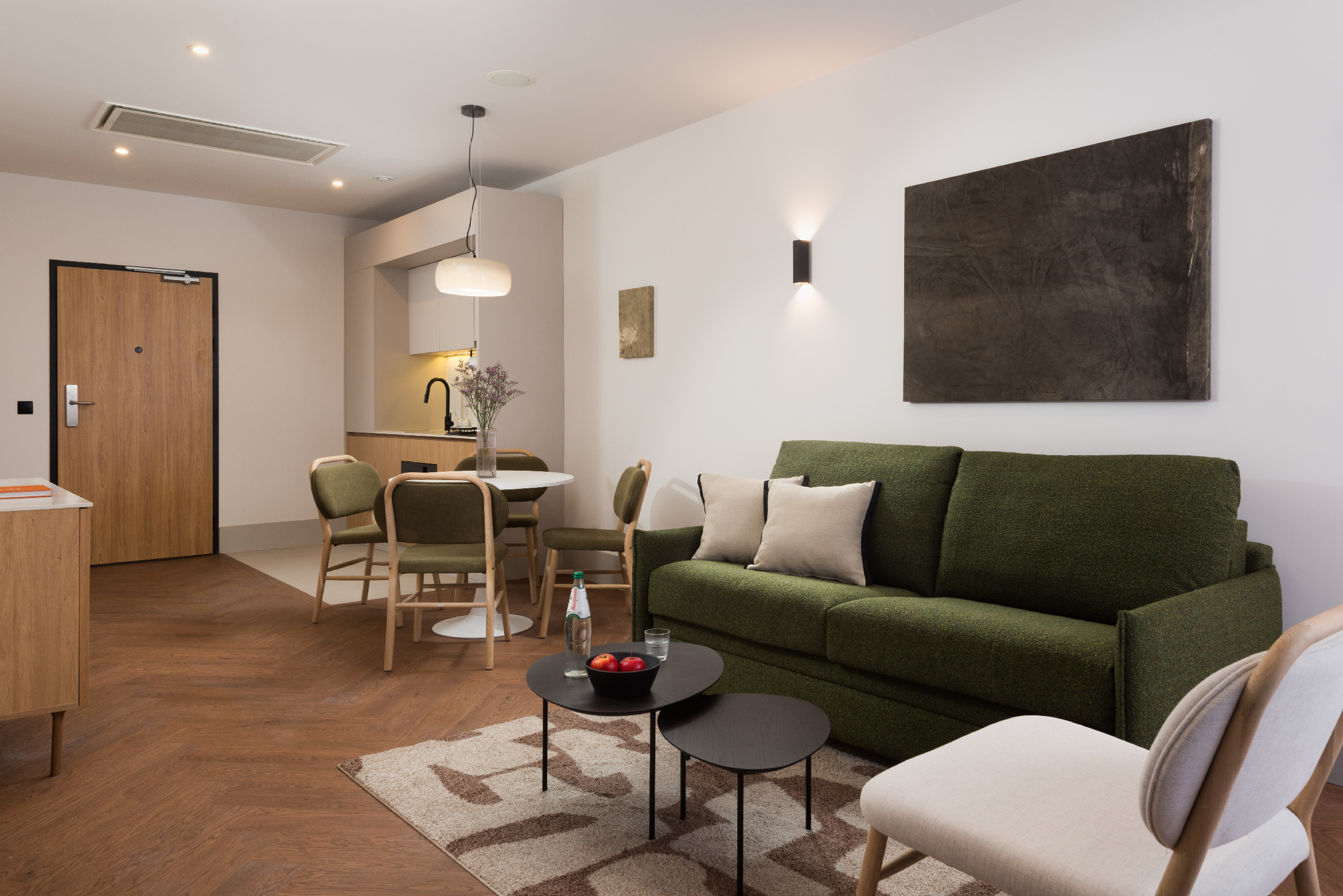 Open-plan apartment living space at master Wola Serviced Apartments with seating area and dining table