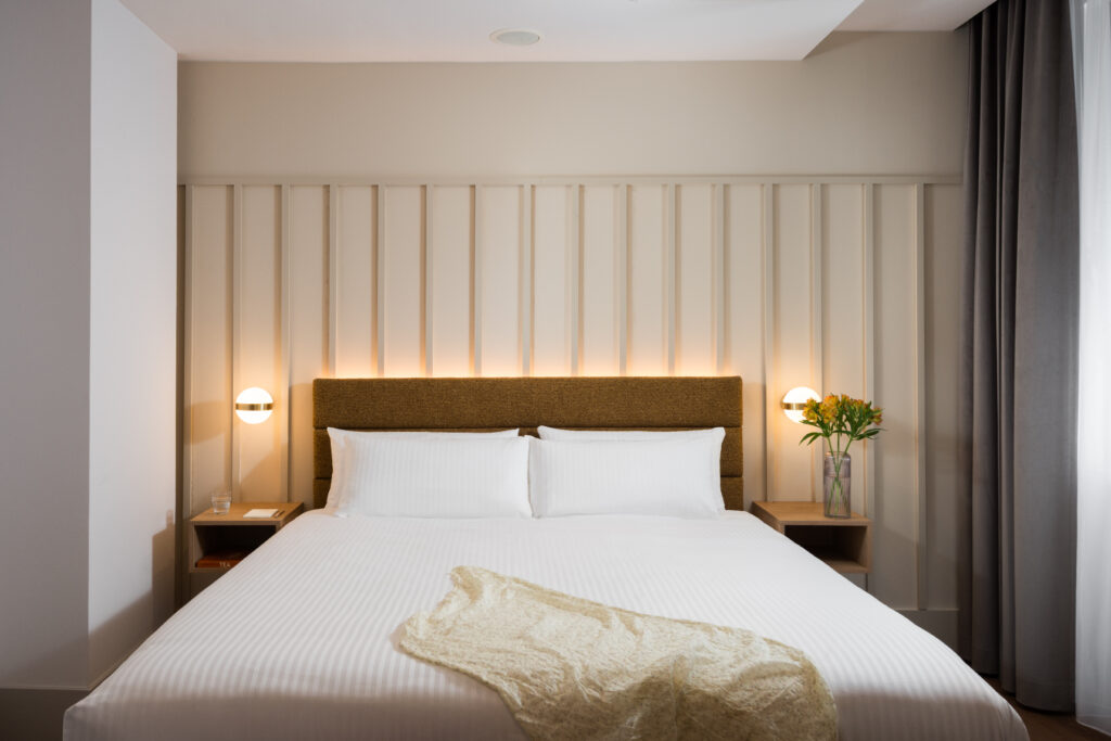 Comfortable bedroom at master Wola Serviced Apartments with double bed, bedside lighting, and warm neutral design