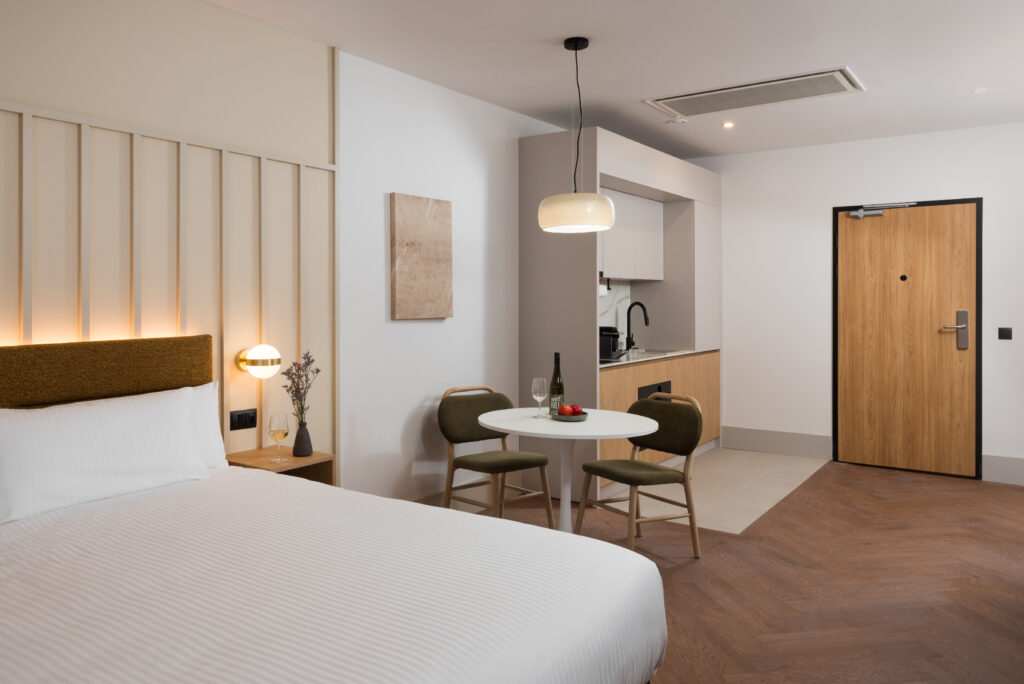 Studio apartment interior at master Wola Serviced Apartments featuring sleeping area, dining table, and kitchenette