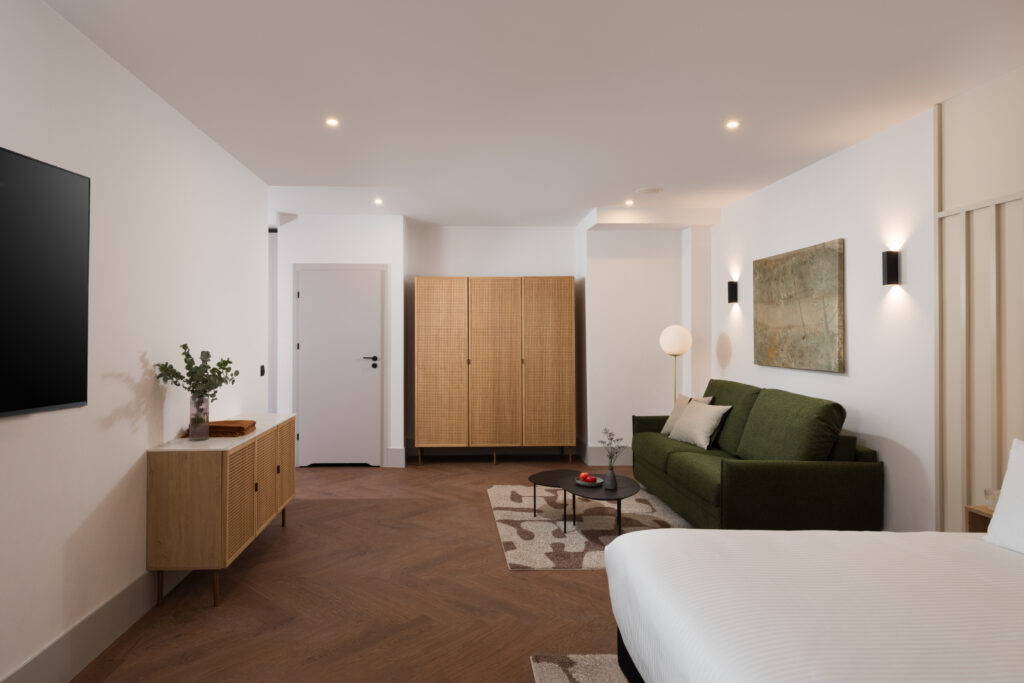 Studio apartment living space at master Wola Serviced Apartments with sofa, wardrobe, and warm lighting