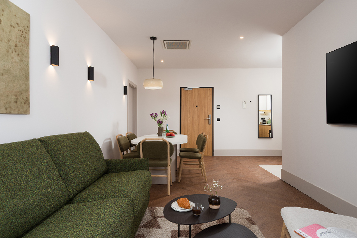 Open-plan living and dining area in master Wola two bedroom apartment with dining table, sofa, and modern interior.