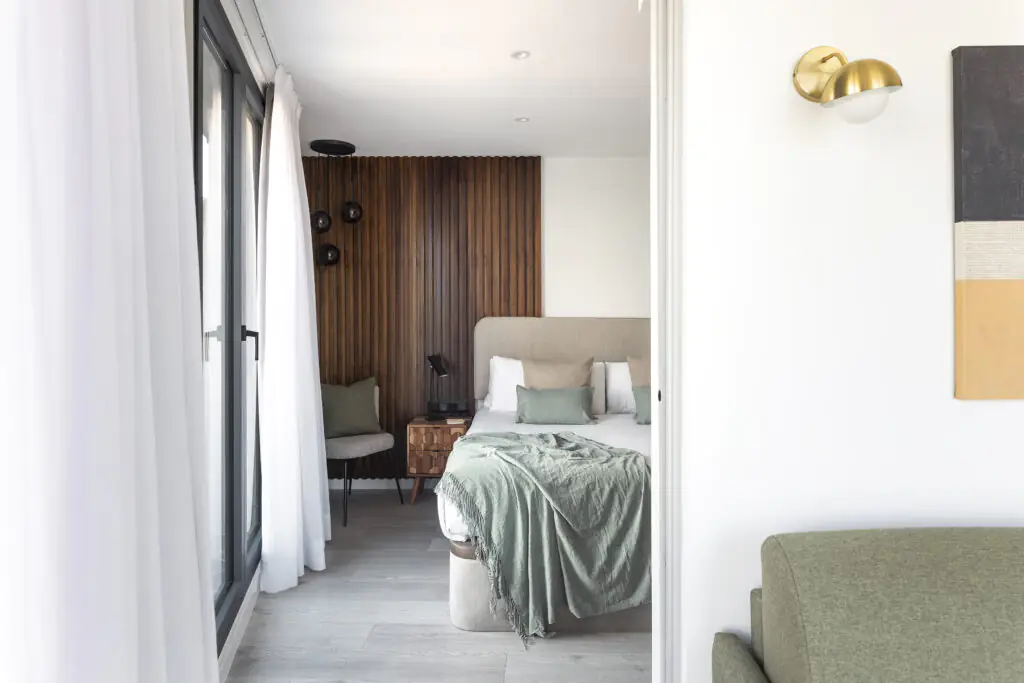 Stylish bedroom at master La Rambla Barcelona with soft-toned bedding, wood-paneled accent wall, and private balcony access.