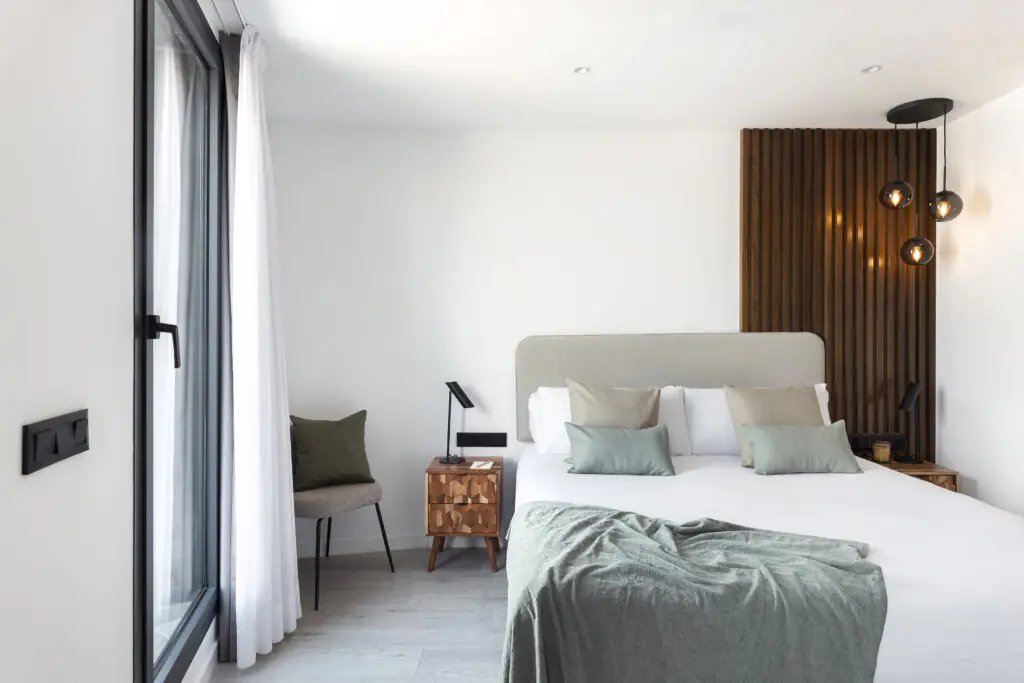 Stylish bedroom at master La Rambla Barcelona featuring modern design, soft-toned bedding, and floor-to-ceiling windows.
