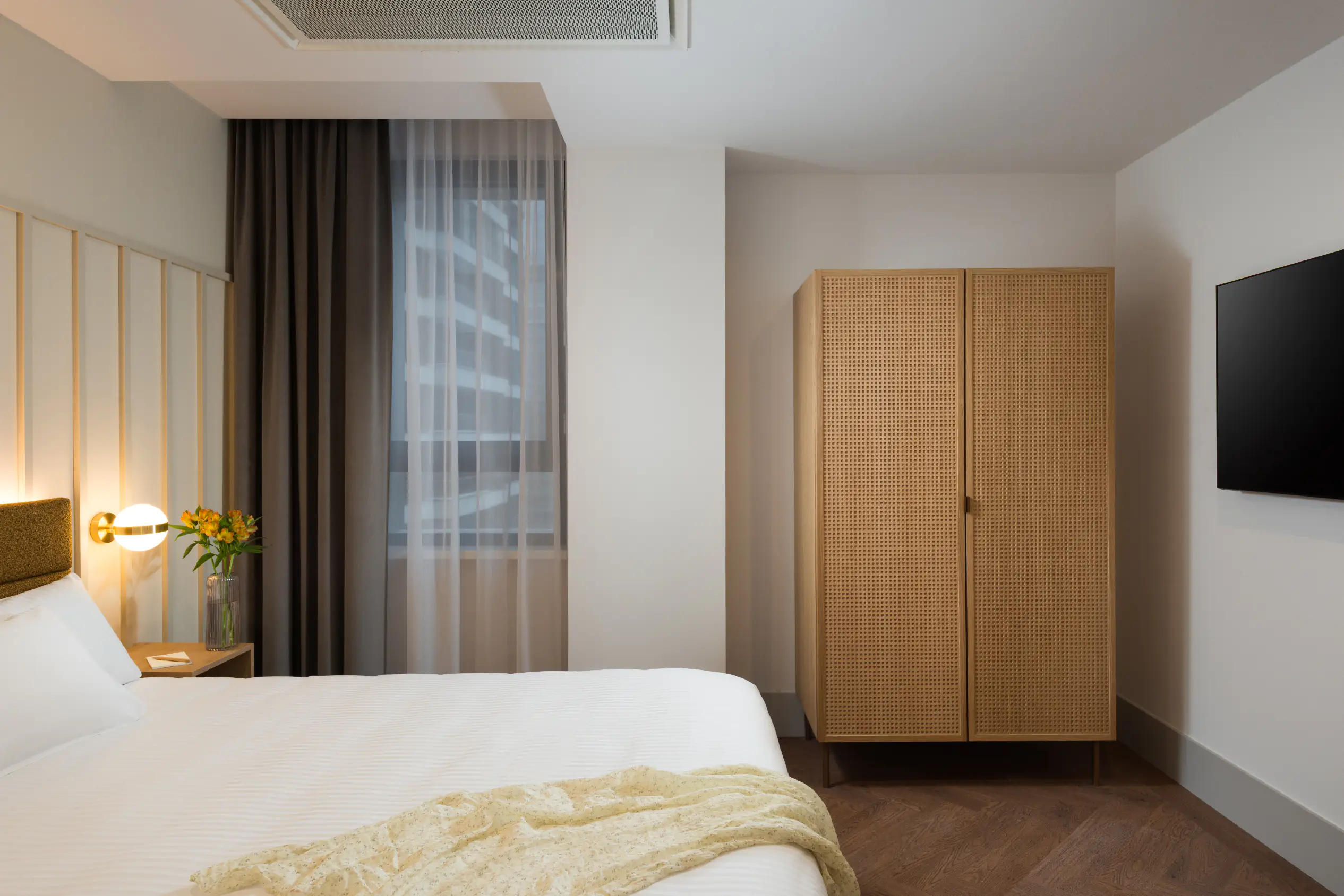 One-bedroom apartment bedroom at master Wola Serviced Apartments with double bed, wardrobe, and soft natural lighting