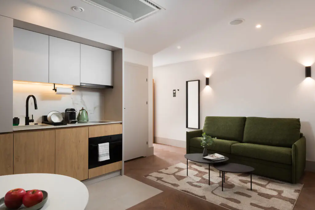 Studio apartment kitchenette and living area at master Wola Serviced Apartments with sofa and coffee table