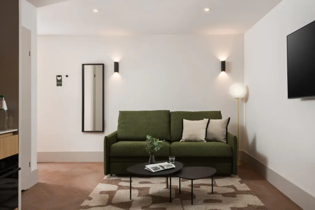 Comfortable seating area in a studio apartment at master Wola Serviced Apartments with green sofa and coffee table